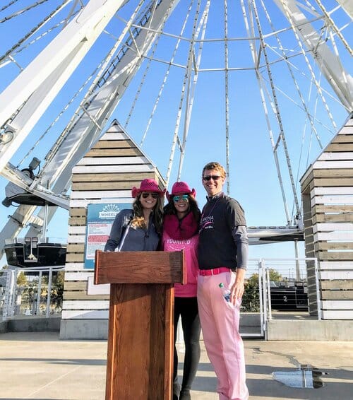 three people smiling in front of a ferris wheel