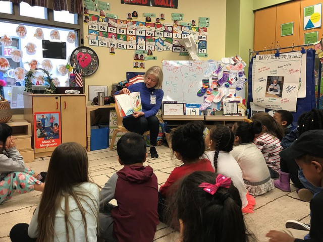 Woman reading a book to children in a classroom